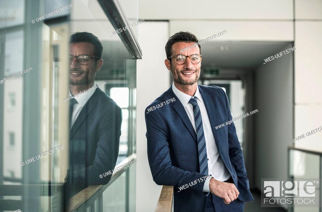 Stock Photo: Portrait of a successful businessman, standing in office building.