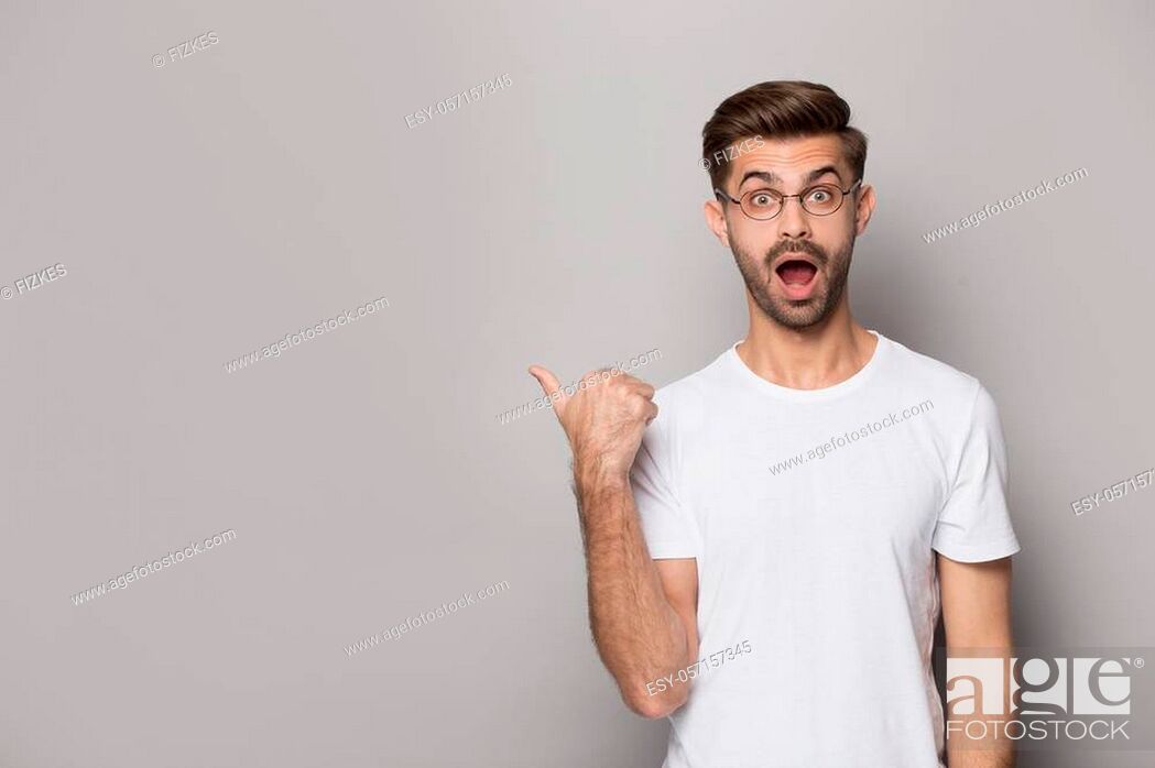 Stock Photo: Amazed funny guy wearing white t-shirt glasses point finger aside at copy space advertise better offer huge discount opportunity.