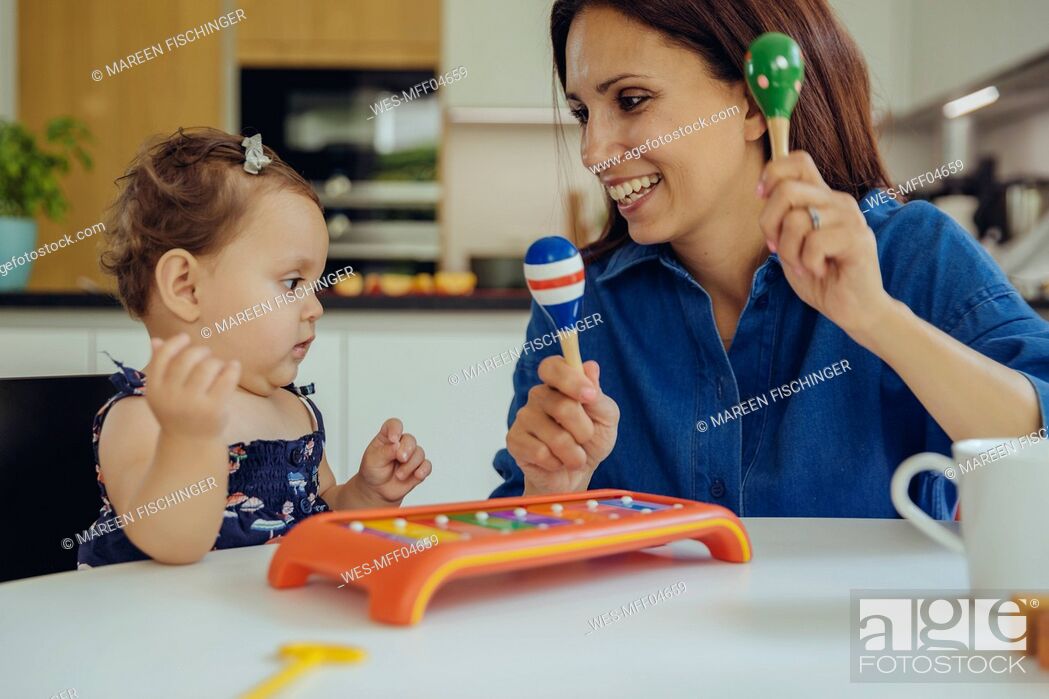 Stock Photo: Happy mother and baby daughter playing with rattles.