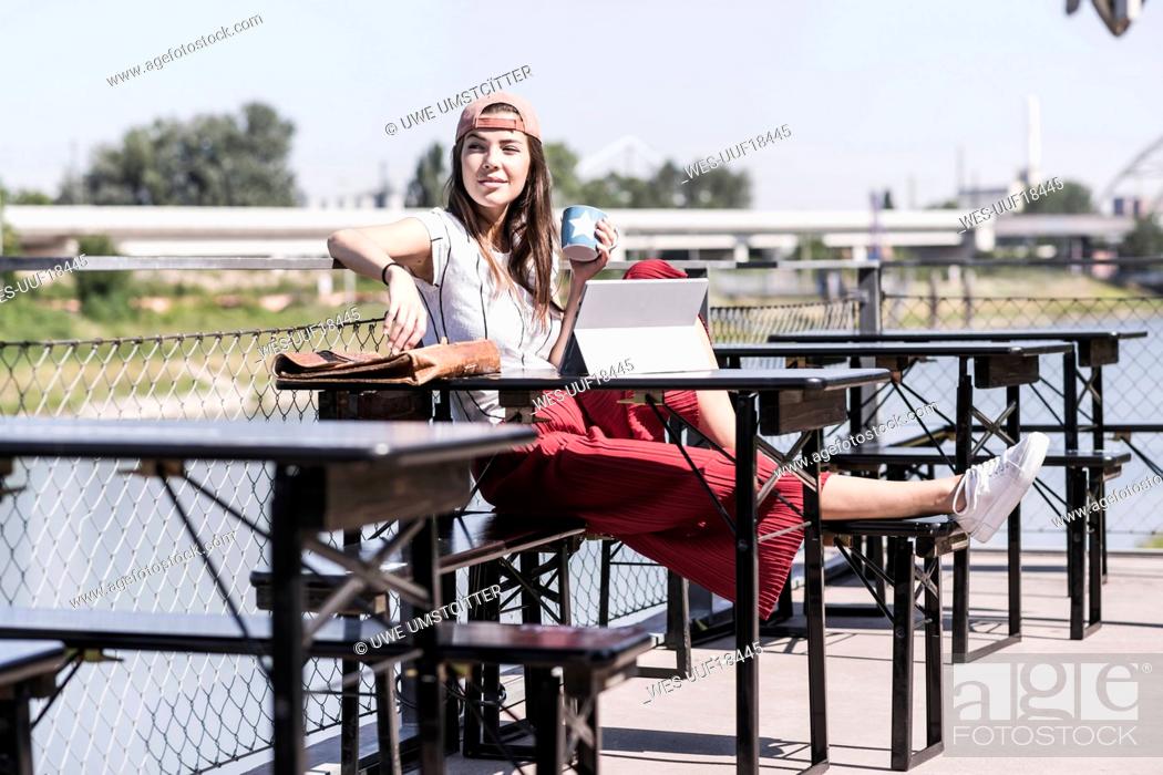 Stock Photo: Young woman relaxing in a beer garden looking around.