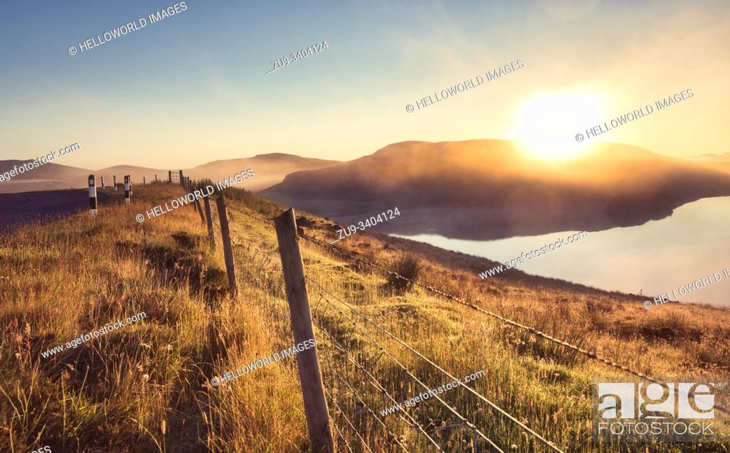 Stock Photo: Misty summer sunrise over loch with reflection and barbed wire fence, Isle of Lewis, Outer Hebrides, Scotland.