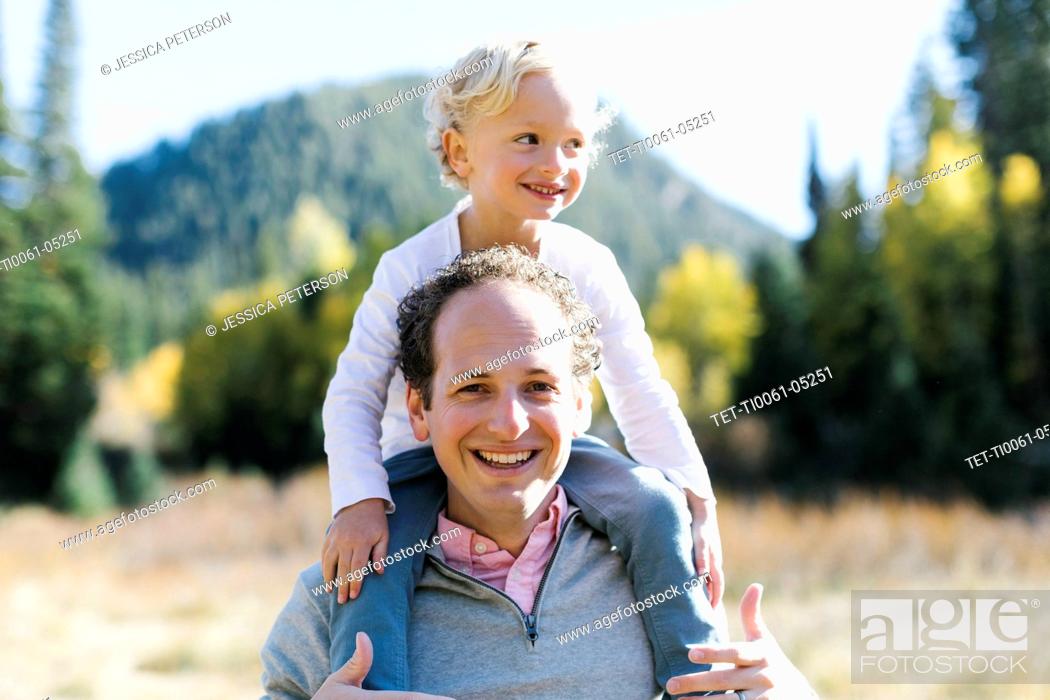 Stock Photo: Son sitting on father's shoulders in nature.