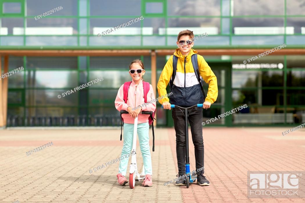Photo de stock: happy school children with backpacks and scooters.