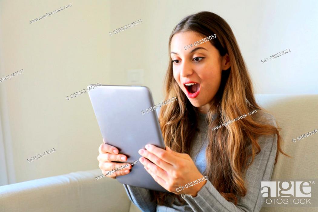 Stock Photo: Happy girl using tablet. Excited woman holding tablet pc .on sofa at home.