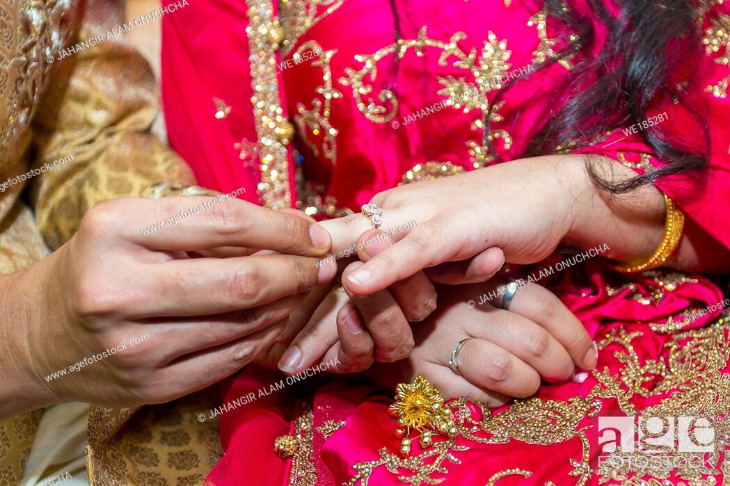 Closeup shot of an Indian couple putting on rings at their wedding Stock  Photo by wirestock
