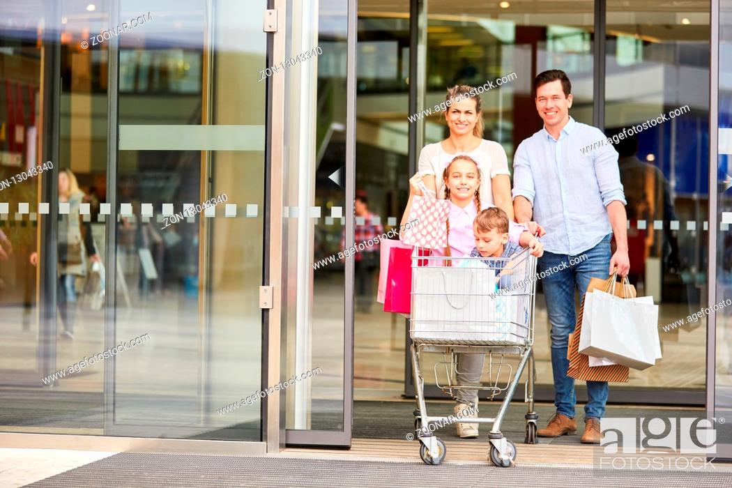 Stock Photo: Glückliche Familie und zwei Kinder im Einkaufswagen mit vielen Einkaufstüten.