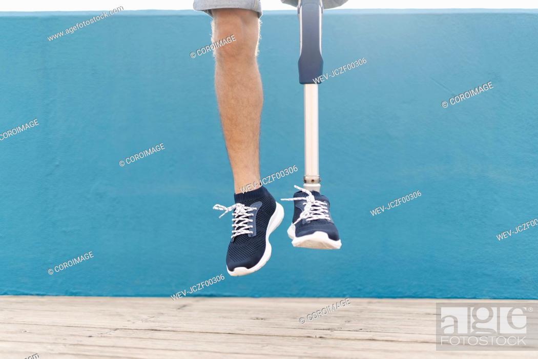 Stock Photo: Disabled man jumping against blue wall.
