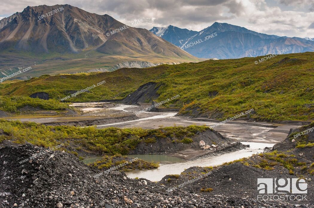 Stock Photo: Thorofare River flowing next to the stone and vegatation covered Moldrow Glacier in Denali National Park and Preserve, Mount Eielson and the Alaska Range in the.