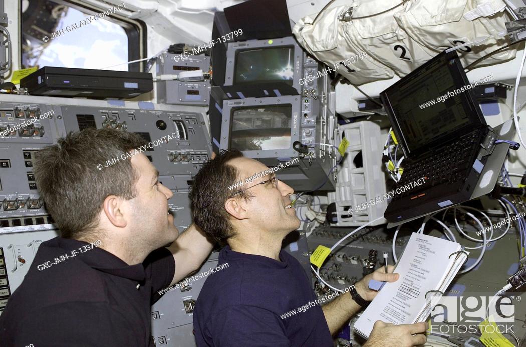 Stock Photo: Astronauts Stephen N. Frick (left), STS-110 pilot, and Carl E. Walz, Expedition Four flight engineer, work with Payload and General Support Computers (PGSC) on.