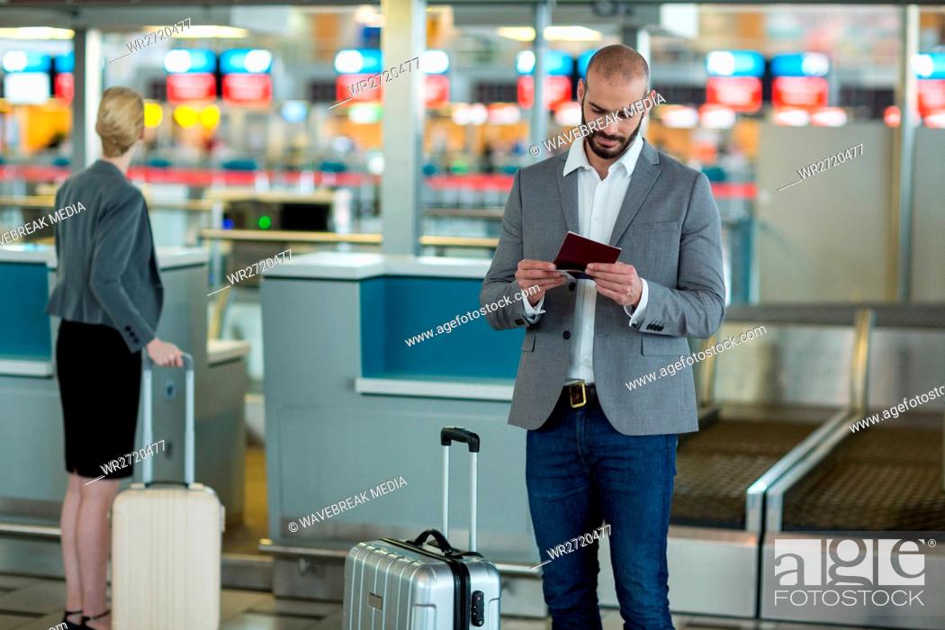 Stock Photo: Businessman with luggage checking his boarding pass.