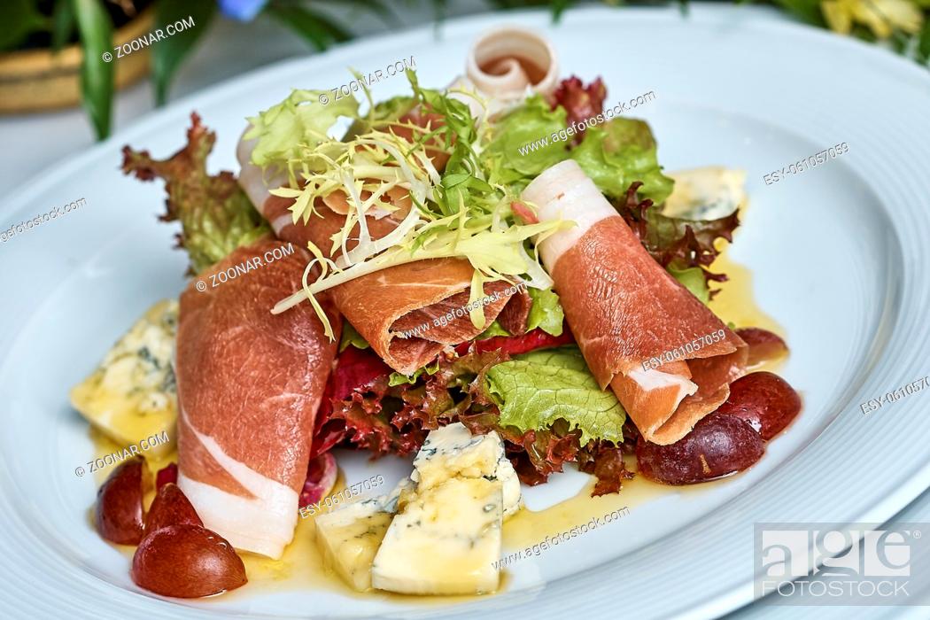 Stock Photo: meat salad with ham cheese lettuce Dorblu grapes and olive oil served on a plate on a table with flowers.