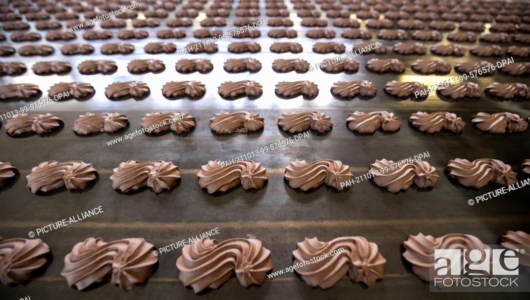 Stock Photo: PRODUCTION - 29 September 2021, Bavaria, Nuremberg: Chocolate spritz cookies lie on a conveyor belt in production at gingerbread manufacturer Schmidt.