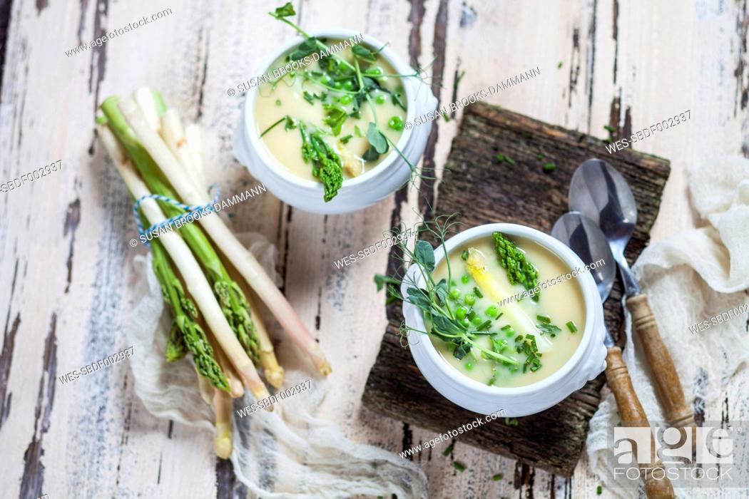Stock Photo: Cream of white asparagus soup garnished with white and green asparagus spears, pea shots and chives.