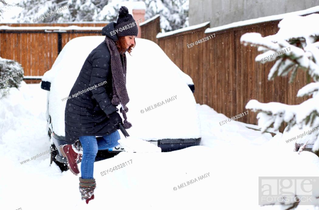 Stock Photo: woman with shovel cleaning snow aeound car. Winter shoveling. Removing snow after blizzard.