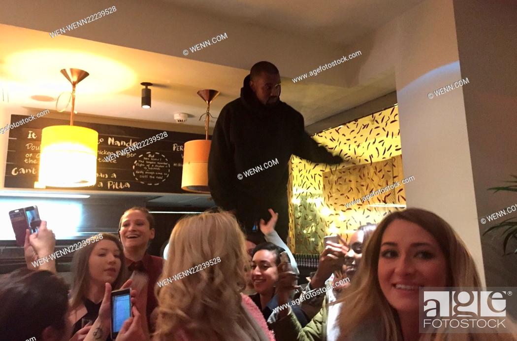 Stock Photo: Kanye West surprised fans by visiting Nandos restaurant in Central London. The star jumped onto a table to allow fans to take selfies with him in the background.