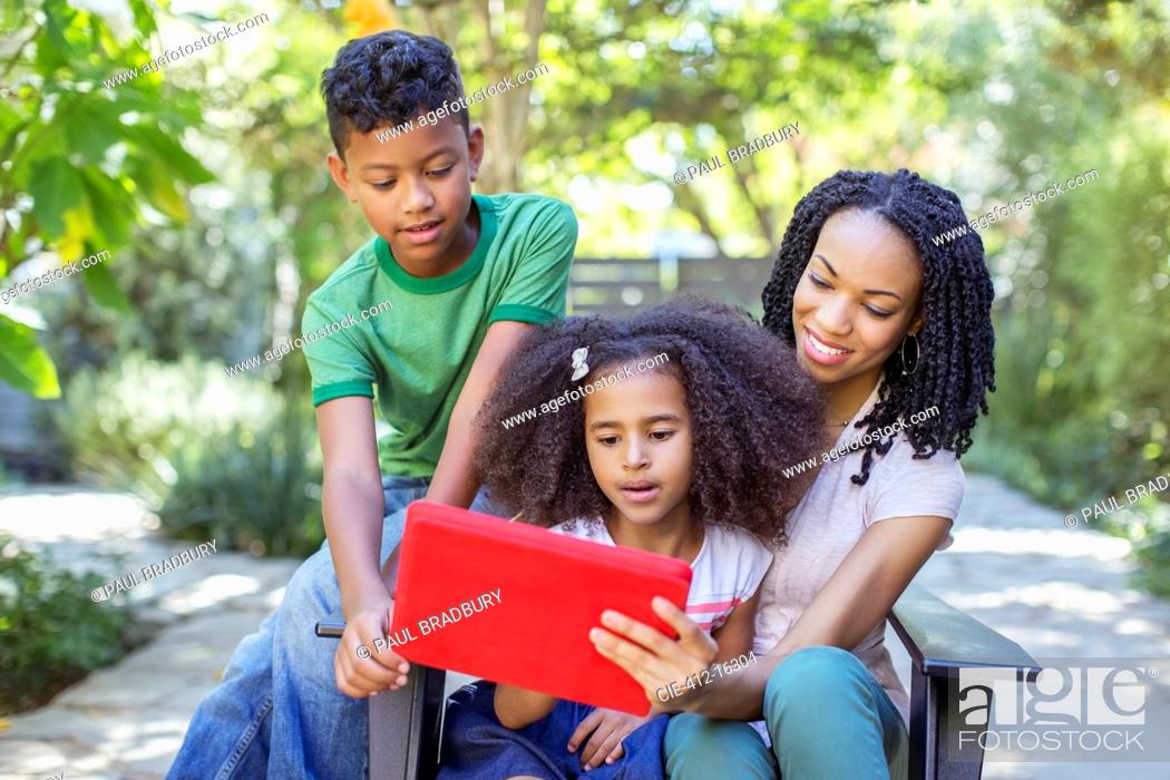 Stock Photo: Mother and children using digital tablet outdoors.
