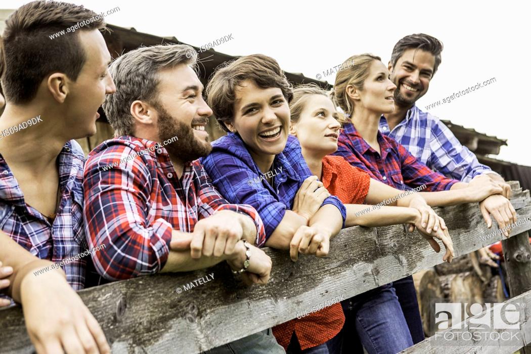 Stock Photo: Group of friends leaning on wooden fence, Tirol, Austria.