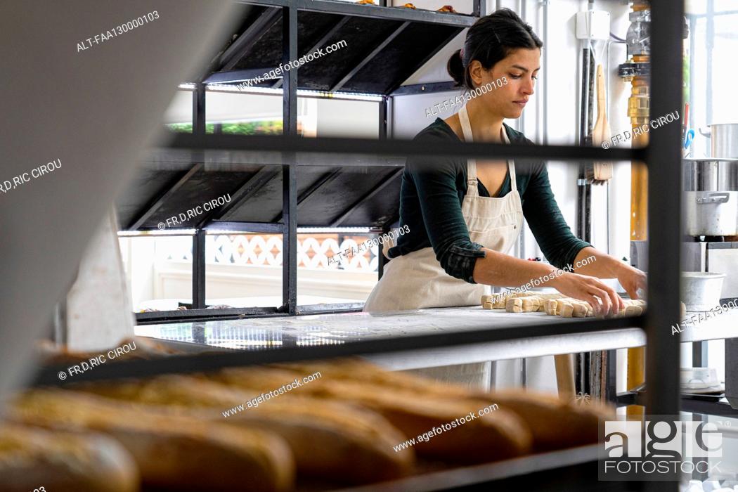 Photo de stock: Wide angle view of female Latin-American bakery owner kneading pastry dough.