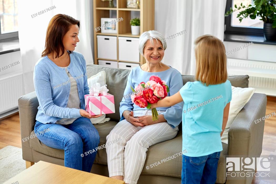 Stock Photo: granddaughter giving flowers to grandmother.