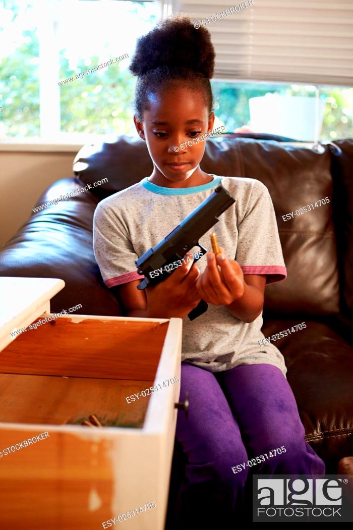 Stock Photo: Girl Playing With Parent's Gun She Has Found At Home.