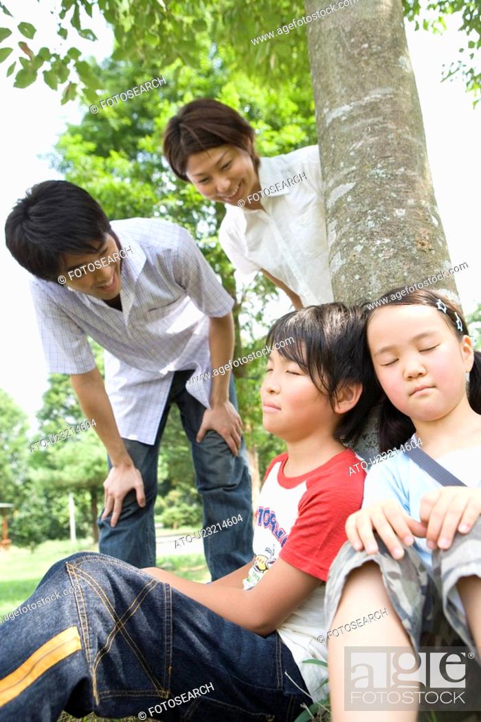 Stock Photo: Parents looking at children sleeping under the tree.