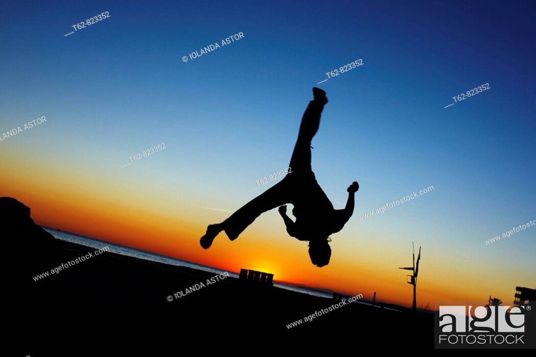 Stock Photo: Parcours: A boy practicing jumps to the dusk in the beach.