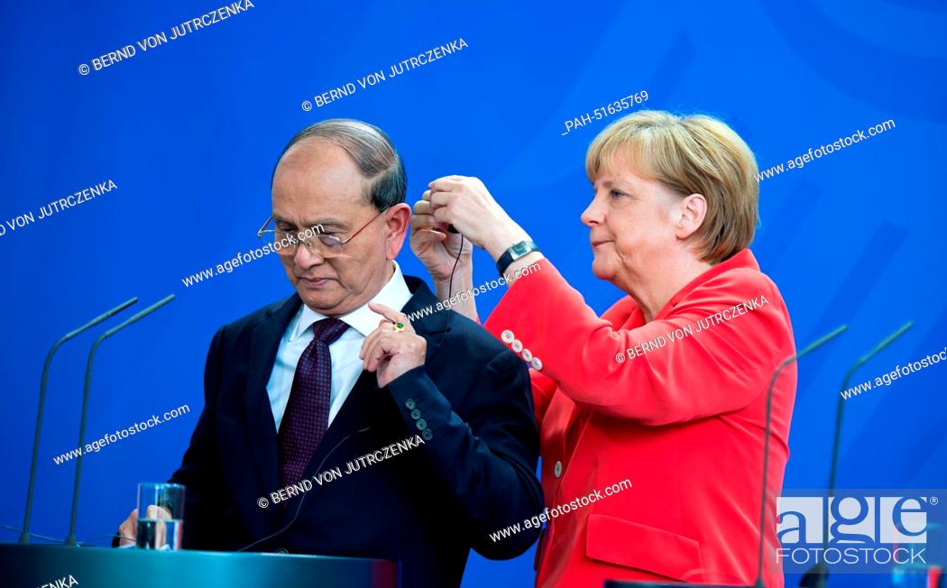 Photo de stock: German Chancellor Angela Merkel (CDU, R) helps the President of Myanmar, Thein Sein, to put on his headphones at the beginning of a press conference in the.