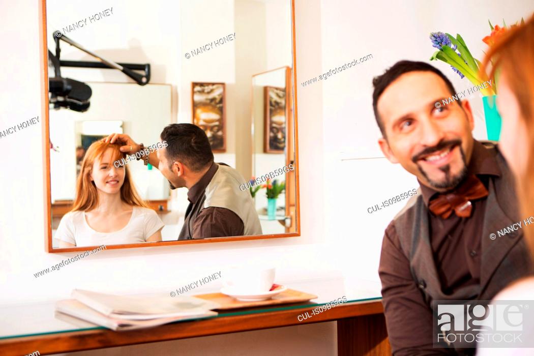 Stock Photo: Male hairdresser advising customer on hairstyle in salon.