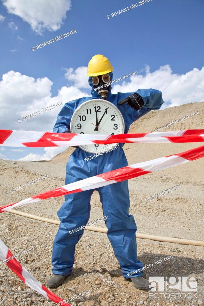 Stock Photo: Germany, Bavaria, Man in protective wear with clock near sand dune and cordon tape in foreground.