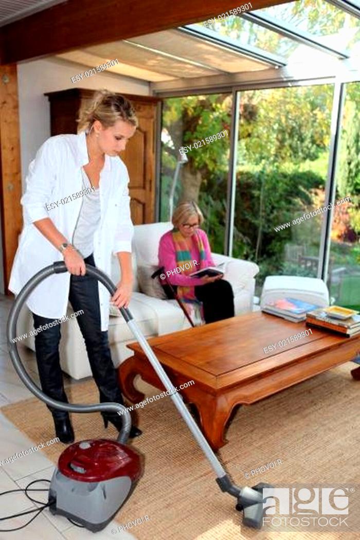 Imagen: Girl vacuuming for an elderly woman.