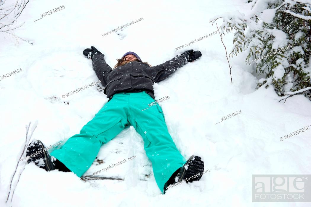 Stock Photo: Woman doing snow angel on beautiful snowy day.