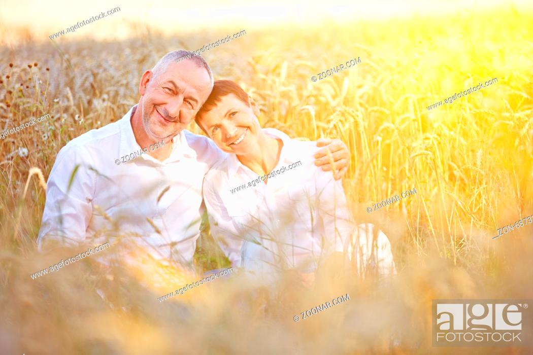 Stock Photo: Paar Senioren macht Urlaub in der Natur und sitzt glücklich in einem Weizenfeld.