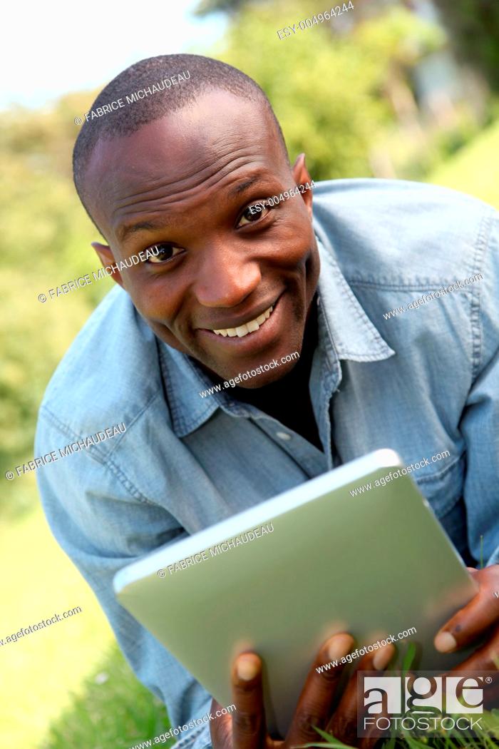 Stock Photo: Man laying down in park with electronic tablet.