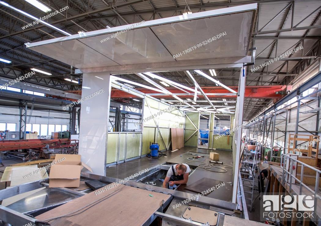 Stock Photo: 25 May 2019, Mecklenburg-Western Pomerania, Rechlin: A houseboat is overhauled in the Kuhnle shipyard shipbuilding hall. The boats intended for charter tours on.
