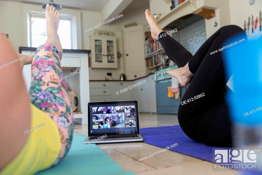 Stock Photo: Women exercising online at laptop on kitchen floor.
