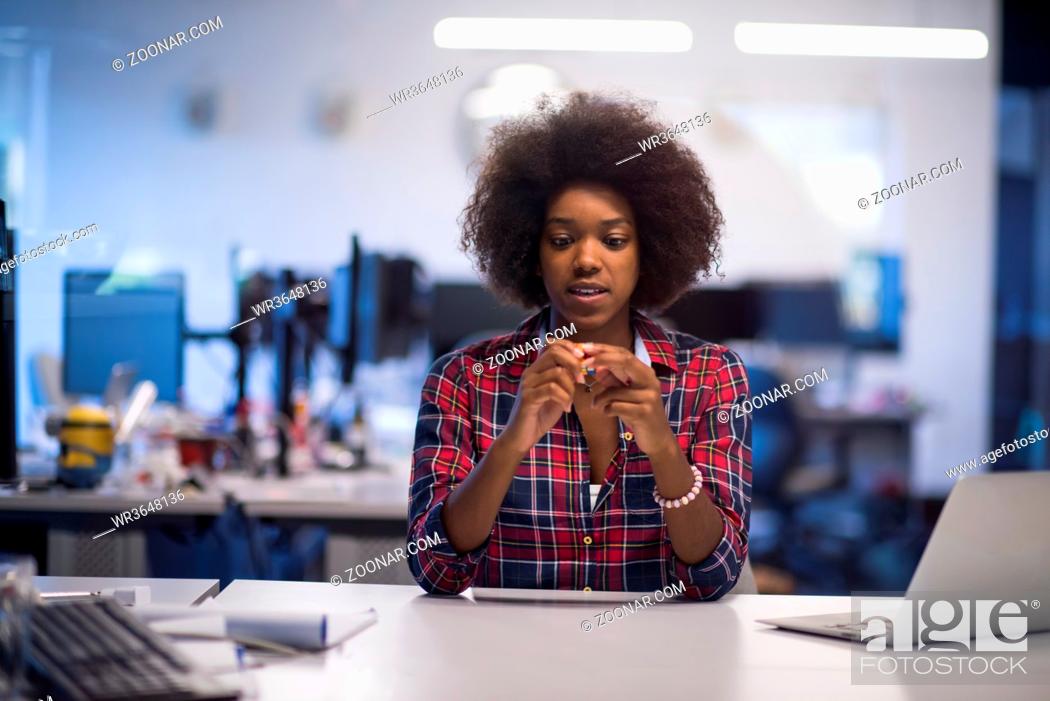 Stock Photo: portrait of a young successful African American beautiful woman who enjoys spending a quality and joyful time while working in a large modern office.