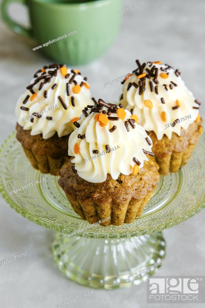 Stock Photo: Spiced carrot and nut Autumn cupcakes, decorated with cream cheese frosting and sprinkles.