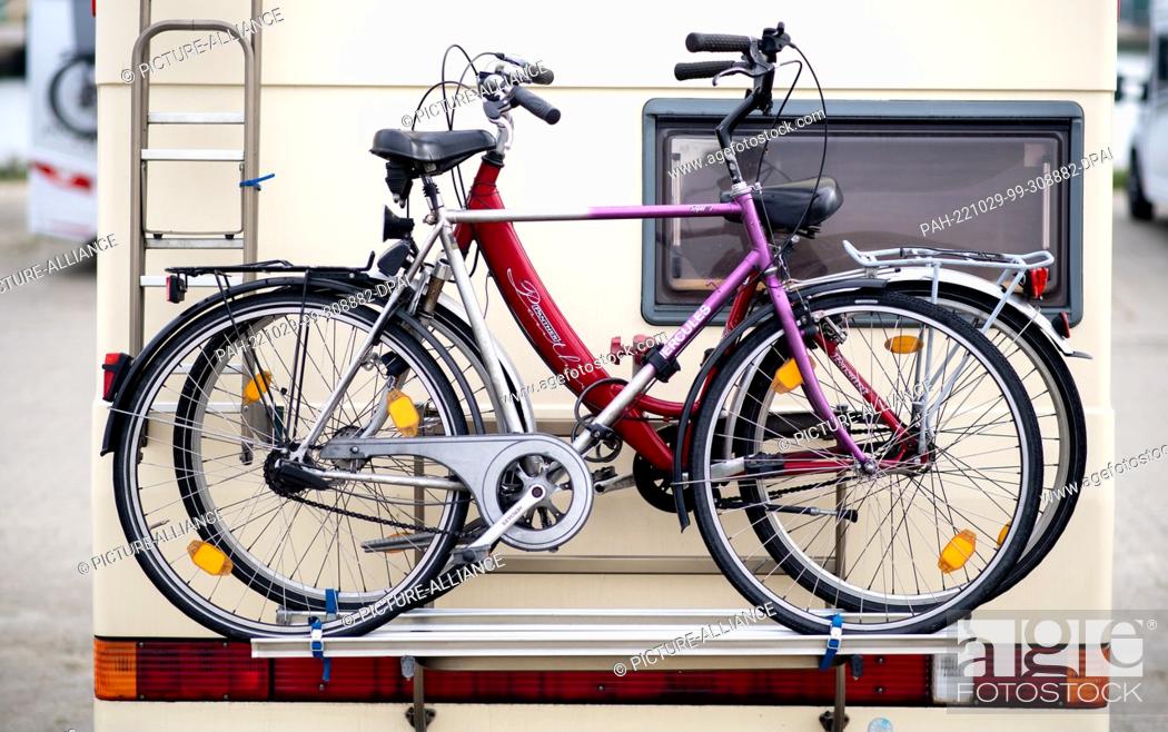 Stock Photo: 29 October 2022, Lower Saxony, Harlesiel: Bicycles stand on a bicycle rack on a mobile home on a parking space at the pier.
