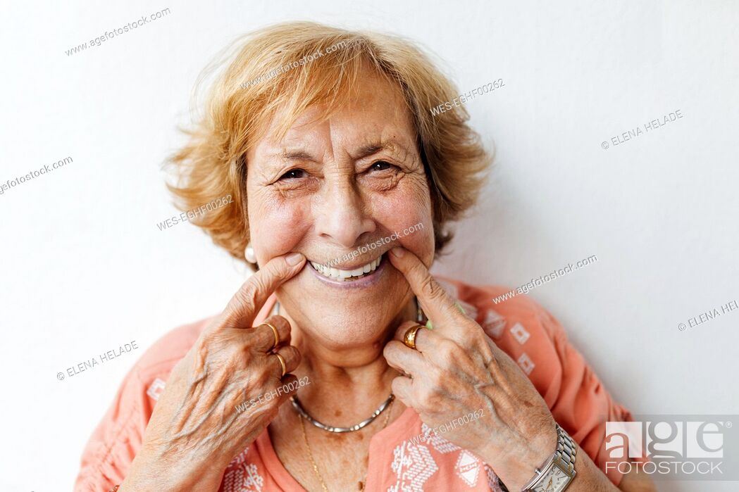Imagen: Senior woman holding cheeks in front of white wall.