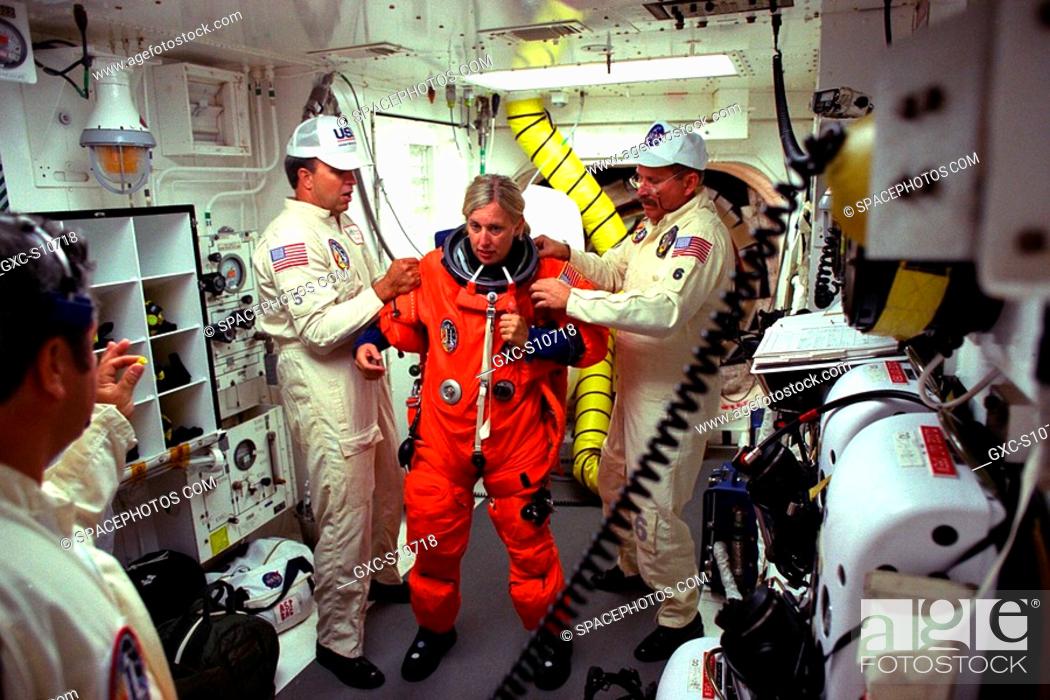 Stock Photo: 08/07/1997 --- STS-85 Payload Commander N. Jan Davis is assisted with her ascent/reentry flight suit by white room closeout crew members Dave Law left and Jack.