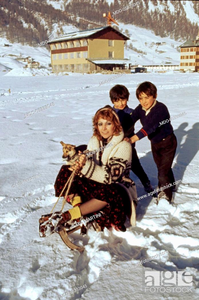 Stock Photo: The singer Mia Martini (Domenica Rita Adriana Bertè) playing in the snow with two children. Livigno, Italy. 1973.