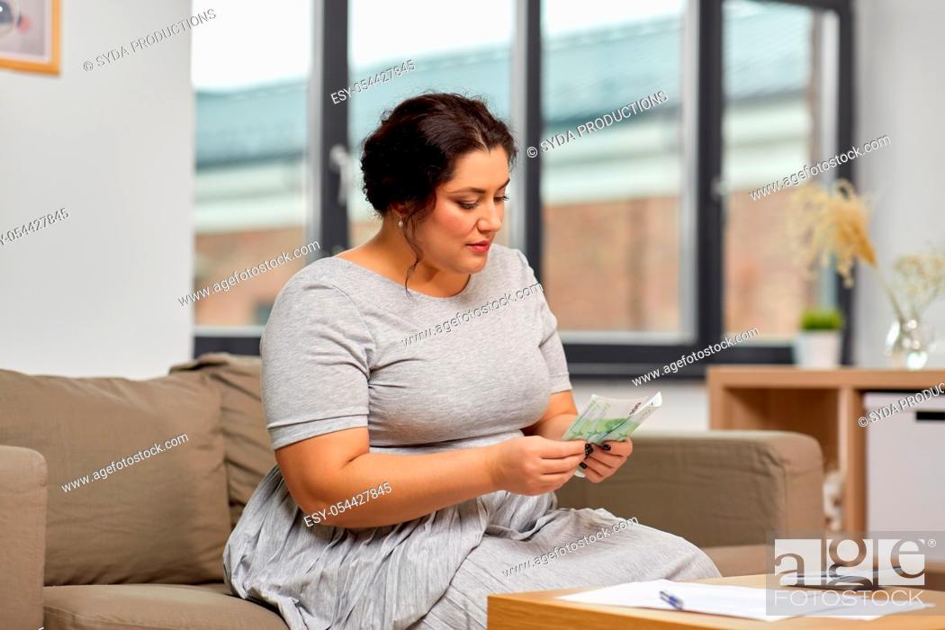 Stock Photo: woman with money, papers and calculator at home.