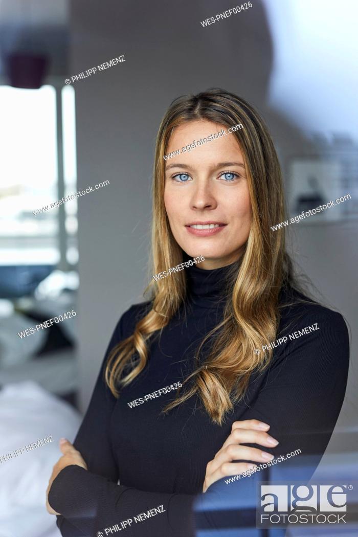 Stock Photo: Portrait of smiling young woman wearing black turtleneck behind windowpane.
