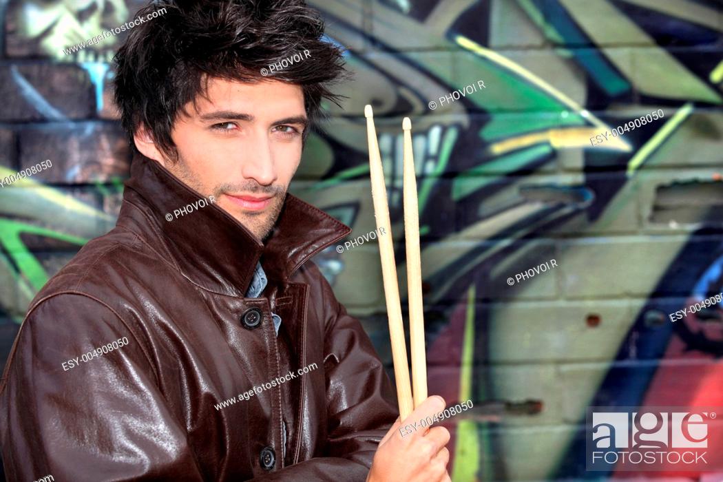 Stock Photo: musician with drumsticks against graffiti wall.