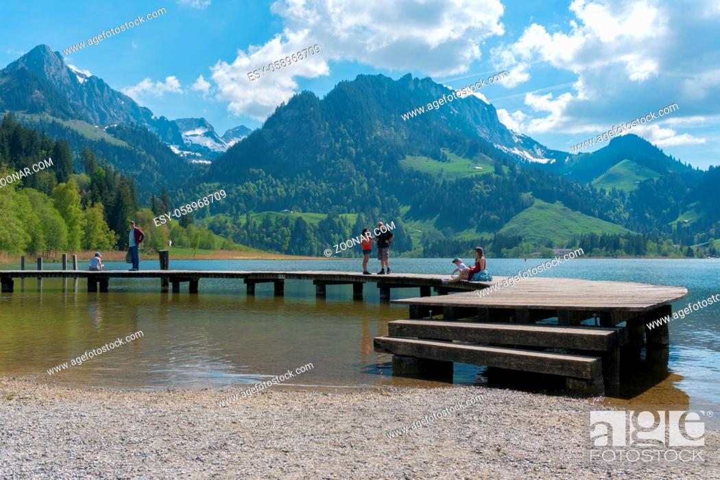Stock Photo: Schwarzsee, FR / Switzerland - 1 June 2019: tourist people enjoy a visit to Lake Schwarzsee in Fribourg as a family vacation destination in the Swiss Alps.