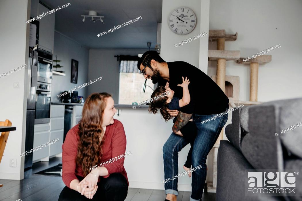 Stock Photo: Mother looking at father playing with daughter.
