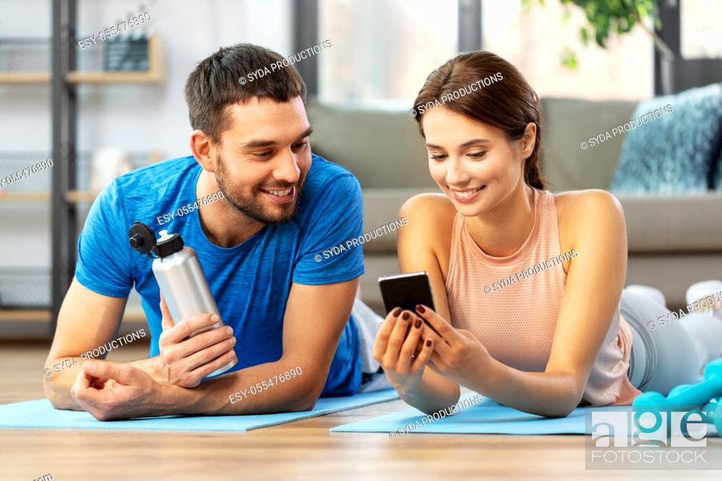 Stock Photo: happy couple with smartphone after sports at home.