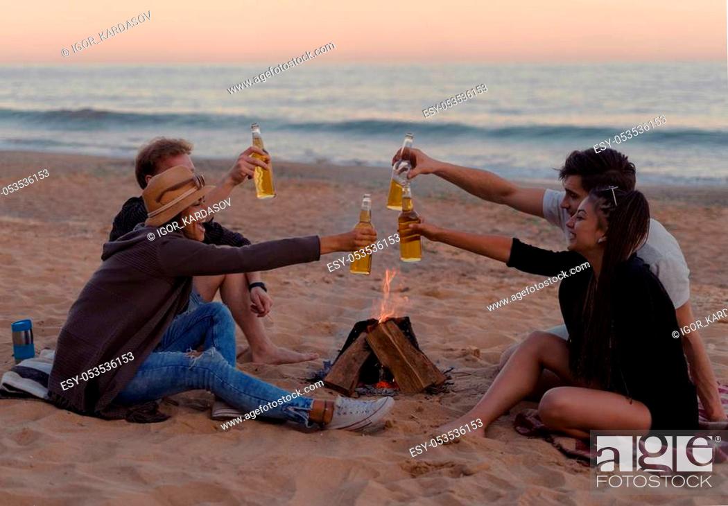 Photo de stock: cheers. group of friends on the beach party drinking alcohol and clink glasses. Happy youth time.