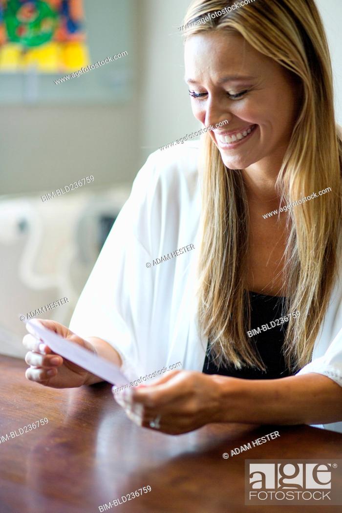 Stock Photo: Caucasian woman reading invitation.