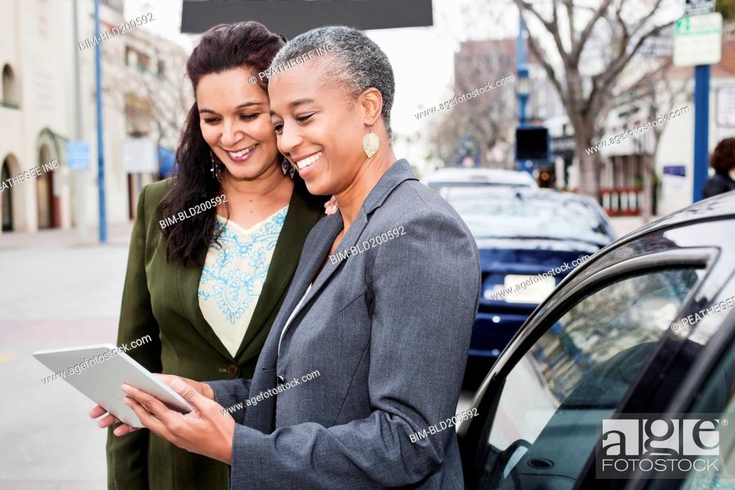 Stock Photo: Businesswomen looking at digital tablet outdoors.
